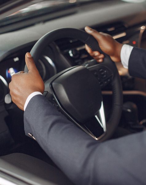 Man buying the car. Businessman in a car salon. Black male in a suit.